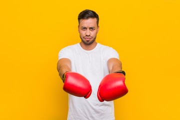 Young south-asian boxer man wearing red gloves.