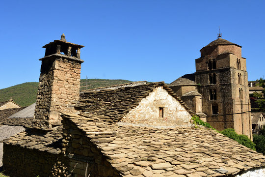 roof with traditional chimney and Church of Santa Maria, Santa Cruz de la Seros. Huesca. Aragon, Spain