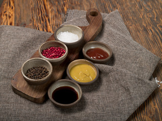Obraz na płótnie Canvas Different spices and sauces with a gray linen tablecloth on a wooden background, studio lighting, top view