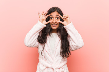 Young indian woman wearing pajama keeping eyes opened to find a success opportunity.