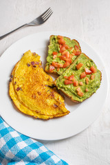 Healthy breakfast with omelette and guacamole toast on white background