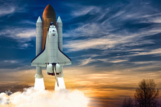 A shuttle spaceship launch on background of blue night cloudy sky.