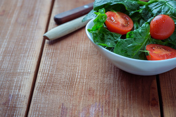 summer salad with tomatoes in white plate on wood table