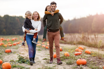 Happy young family in pumpkin patch field