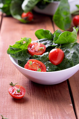 summer salad with tomatoes in white plate on wood table
