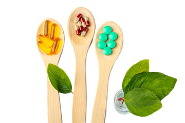 Herbal capsule, nature vitamins, mineral supplement pills at wooden spoon isolated on white background. Concept of healthcare and alternative medicine: homeopathy and naturopathy. Copyspace for text