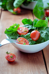summer salad with tomatoes in white plate on wood table