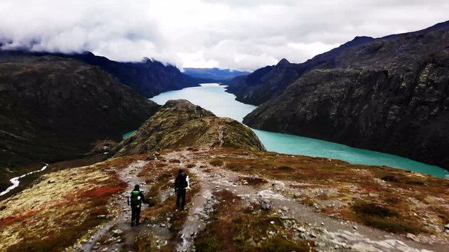 Colorful, impressive view at a large Norwegian fjord with two men hiking (4K, Aerial)