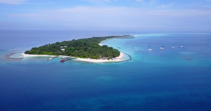 aerial wide view of a tropical island with luxury resorts drone pedestal upshot