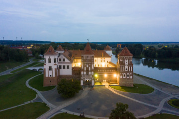 Fototapeta na wymiar Mir Castle and its reflection in the lake in summer. Twilight and late evening. Aerial view from a drone