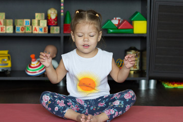 Fototapeta Cute little girl sitting in yoga pose with closed eyes indoor obraz