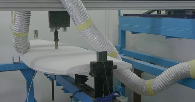 Surfboard being shaped by a machine in a workshop