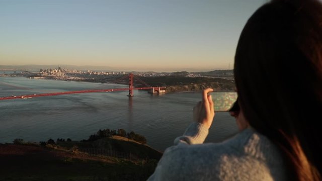 Woman photographing the Golden Gate Bridge, San Francisco
