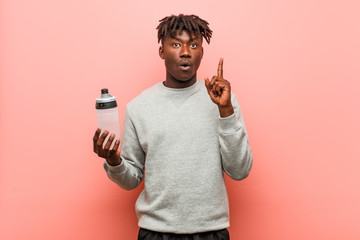Young fitness black man holding a water bottle having some great idea, concept of creativity.