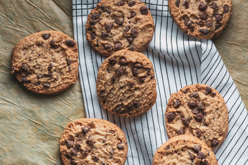 Homemade chocolate cookies on baking paper and white cloth.