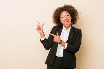 Young business african american woman pointing with forefingers to a copy space, expressing...