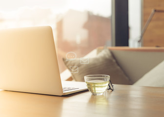 Freelance Desk with open laptop, cup of green tea and glasses on table. Cafe or coworking space. Concept of digital nomads, home office, blogging