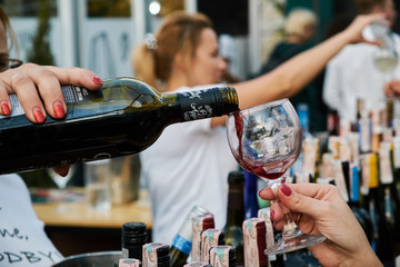 Female hand pours wine into a glass