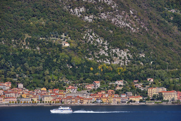 Fototapeta na wymiar Panoramic view of Lake Como. Lombardy, Italy. Boat in motion on the water. Autumn season.
