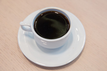 white cup, coffee in white sauce.Cup of hot coffee on table in cafe blur background . coffee beans in white porcelain cup decorated wild herbs .