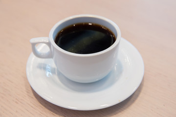 white cup, coffee in white sauce.Cup of hot coffee on table in cafe blur background . coffee beans in white porcelain cup decorated wild herbs .