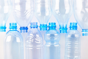 Set of empty different type water bottles lie isolated on white, top view. Plastic production and...