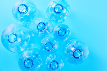 Set of empty different type water bottles lie isolated on blue background, top view. Plastic production and processing concept