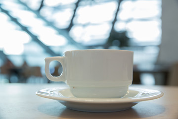 white cup, coffee in white sauce.Cup of hot coffee on table in cafe blur background . coffee beans in white porcelain cup decorated wild herbs .