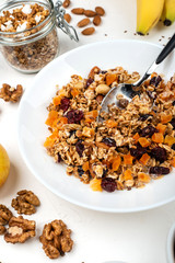 Granola muesli breakfast with with milk, dried apricots, cranberries, almonds and flax seeds in bowl on a white background. Healthy cereal breakfast.