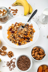 Granola muesli breakfast with with milk, dried apricots, cranberries, almonds and flax seeds in bowl on a white background. Healthy cereal breakfast.