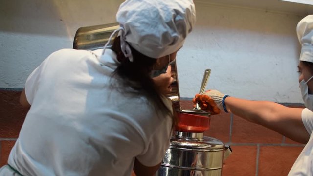 Woman pouring fermented alcoholic juice in stainless dispenser  in a home based winery.