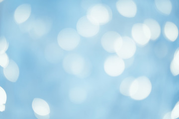 Winter holidays concept. Blur white circle lights. Defocused sky blue abstract background. Falling snow flakes effect.