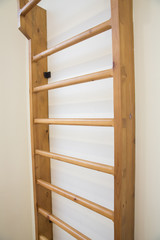 wooden wall bars ladder in big empty gym room of school . wooden back in the school gym for student exercises .