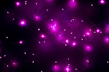 Cold white LED string lights on star pattern purple background. Modern festive interior decor.