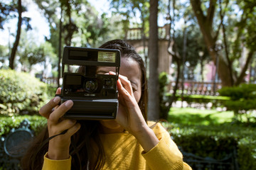 Woman taking photos in the park with instant camera