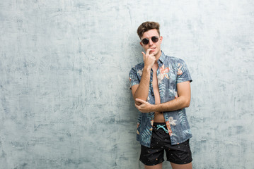 Fototapeta na wymiar Young caucasian man wearing a swimsuit relaxed thinking about something looking at a copy space.