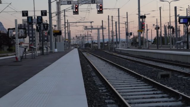 empty train platform next to the tracks without trains during late evening, handheld