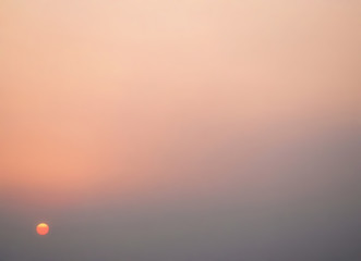 A background of the sky in warm pink and orange shades graduating to grey. The sun is low at sunset or sunrise. Perfect for a gentle and calm background or title page with copy space.