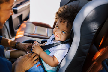 Smiling baby boy looking at his mother while sitting fastened in a car seat - Powered by Adobe