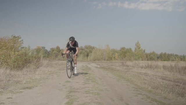 Cycling Race On Gravel Road.Cyclist Riding On Gravel Bike In Slow Motion.Bicycle Racing On Trail. Leader On Race Hurries To Finish Line.Strong Professional Cyclist Athlete On Crosscoutry Competition. 