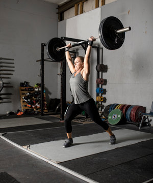 Strong femal weight lifter with heavy weights over her head, two thirds profile shot.