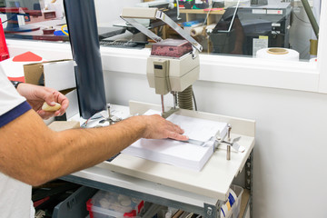 worker manipulating paper punching machine in workshop