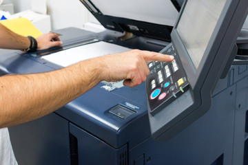 Caucasian adult male hand on the control panel of a photocopier