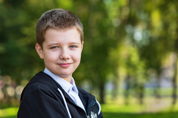 Portrait of smiling 10 year old boy. Happy, chubby boy, outdoors in a park. © Zadvornov
