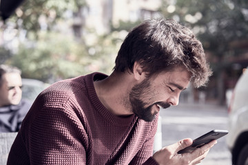 Fototapeta premium Attractive young bearded man using his smartphone in the cafe