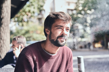 Attractive young bearded man smoking in the cafe