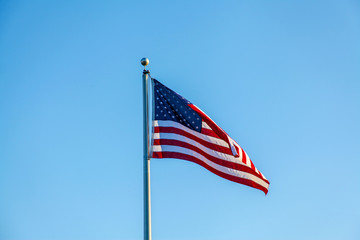 Flag of the United States of America, photograph in the wind, consists of 7 red bands and 6 white bands and a blue rectangle with 50 stars, symbolizing the states of the country.