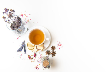 a white mug on a white table with herbal tea and herbal ingredients laid out on the table. Concept...