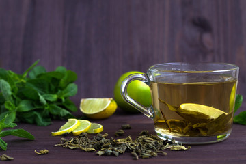 healthy lifestyle. cup of green tea with lemon and mint on wooden background