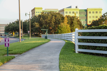 Wide white, curved fence, beside a sidewalk with grass, in the background the beautiful landscape...